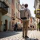 A traveler wearing a slim, lightweight travel backpack walks through a sunny European cobblestone street, representing minimalist travel gear and effortless one-bag travel